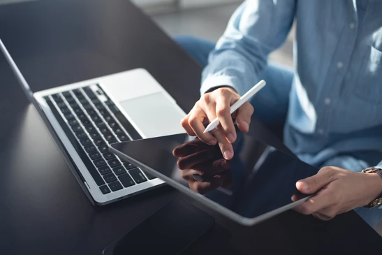 Gros plan professionnel montrant un entrepreneur ou responsable de TPME maritime (personne seule, en tenue business casual) assis à son bureau face à un ordinateur portable, tenant un téléphone ou regardant des documents contractuels, avec en arrière-plan visible par une fenêtre la vue d'un port maritime avec navires et installations portuaires. L'atmosphère doit transmettre la confiance, l'engagement et l'écoute active d'un consultant MAJE envers son client TPME. Lumière naturelle professionnelle, environnement de bureau authentique avec contexte portuaire visible.